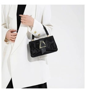 Detail of black leather handbag with embossed letters and a gold geometric metal buckle