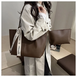 Detail of dark brown leather tote bag set with branded straps and matching pouch