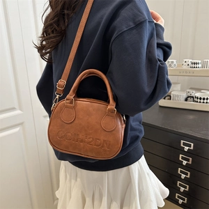 Minimalist vintage brown leather crossbody bag with COIH'2DN logo worn by model