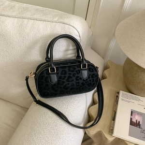 Detail of black leopard print Boston bag on sofa, showing luxury texture and gold hardware