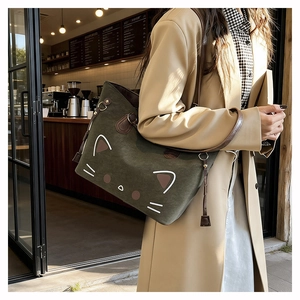 Detail showing dark green canvas tote bag with cat ears and brown leather shoulder strap