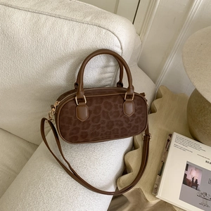 Leopard print crossbody bag with gold hardware on a stylish white sofa setting