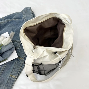Detail of spacious interior and side mesh pocket of this large beige nylon tote bag