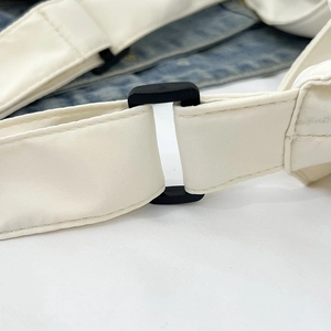 Close-up of white woven adjustable shoulder strap with black plastic buckle and neat stitching