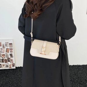 Chic cream small square shoulder bag with gold clasp shown on a person in a black coat