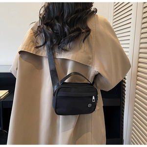 Detail of black waterproof nylon crossbody bag with adjustable strap and metal logo