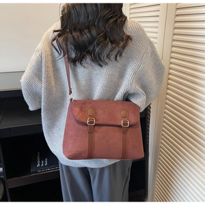 Detail of vintage suede crossbody bag with decorative buckles shown on a model
