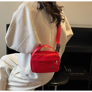 Detail of red nylon crossbody bag with wide adjustable strap and quick-release buckle