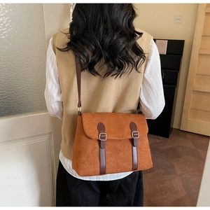 Close-up of a retro brown suede tote bag featuring leather straps and metal buckle details