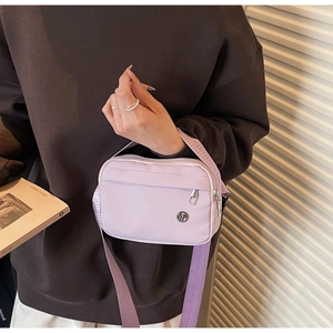 Close-up of lavender nylon crossbody bag with silver zippers and adjustable wide strap