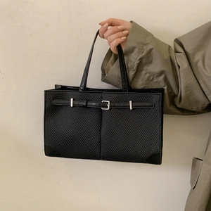 Close-up of black crossbody bag featuring diagonal twill texture and silver hardware details