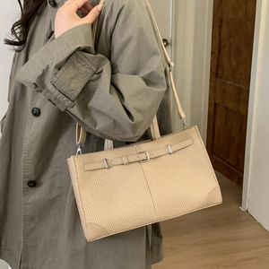 Close-up of beige woven texture bag with leather strap and silver metal buckle