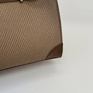 Detail of brown tweed fabric texture and leather stitching on stylish shoulder bag