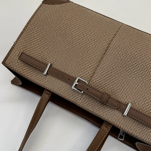 Close-up of brown twill woven tote bag with adjustable leather straps and silver buckle detail