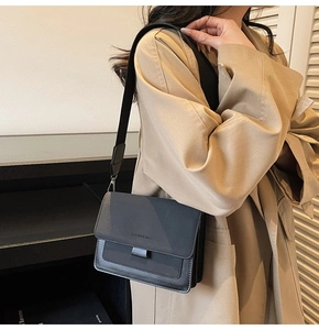 Detail shot of a black PU leather crossbody bag with FASHION & BAGS lettering and wide strap