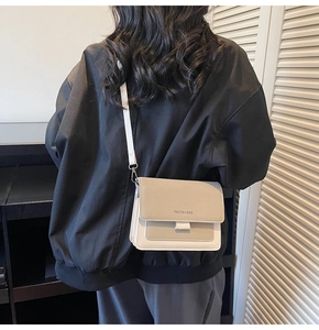 Detail shot of bicolor square crossbody bag with wide strap on model's back view
