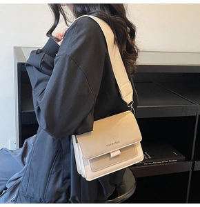 Detail of off-white rectangle crossbody bag with wide fabric strap and fashion logo text