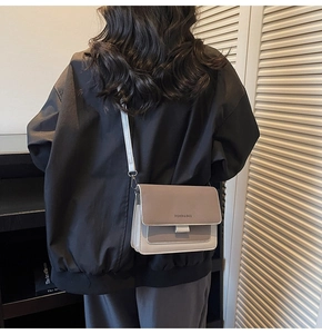 Crossbody bag in brown and white contrast leather worn by a model in a cozy library setting