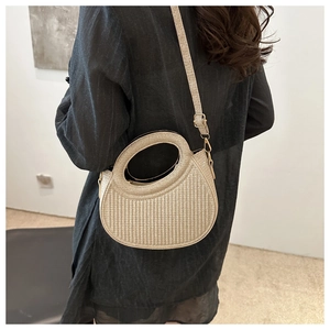 Close-up of woven beige crescent bag with unique circular handle and metallic hardware