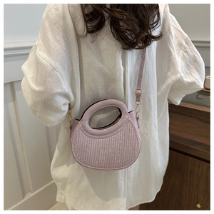 Sparkly pink sequin crossbody bag with round handle shown in a stylish lifestyle scene