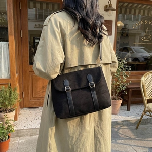Retro black canvas messenger bag with leather straps on a trench coat model