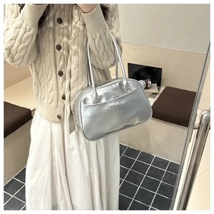 Close-up of metallic silver pillow bag with bow detail and sleek double handle design