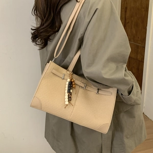 Minimalist beige woven tote bag with leather straps and colorful beaded charm detail