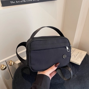 Sac bandoulière en nylon noir minimaliste avec logo en métal, présenté à l'intérieur