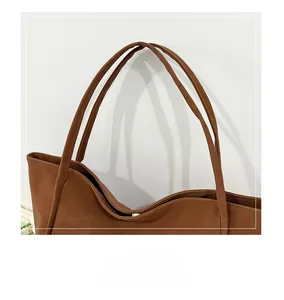 Detail view of brown leather tote bag showing slim handles and golden magnetic closure