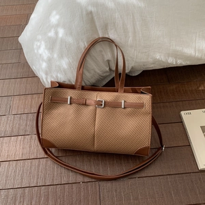 Close-up of brown textured tote bag with metal buckle detail and detachable shoulder strap