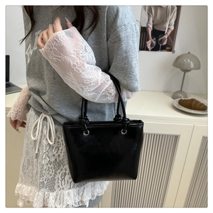 Close-up of glossy black bucket bag featuring decorative knotted straps in chic home setting