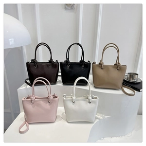 Groupe de sacs seaux minimalistes en cuir en cinq couleurs sur un présentoir blanc