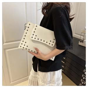 Detail of white envelope clutch bag with square metal rivets held by a fashion model