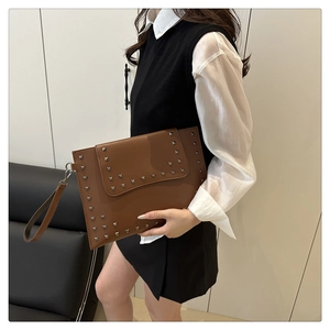 Detail of vintage brown envelope clutch bag featuring silver studs and detachable wrist strap