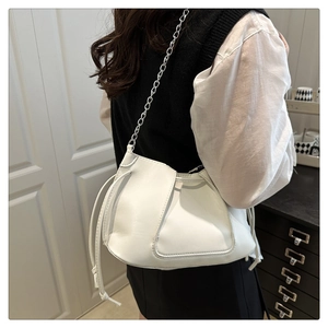 Detail of white drawstring crossbody bag with trapezoid stitching and silver chain