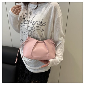 Detail of pink leather shoulder bag with fine stitching, side drawstrings and metal chain