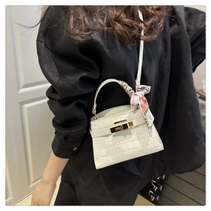 Detail of white crocodile pattern mini bag with silk scarf handle and gold turn-lock