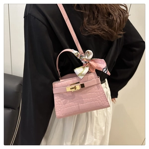 Detail of pink croc-embossed mini bag with gold lock and silk scarf wrapped handle