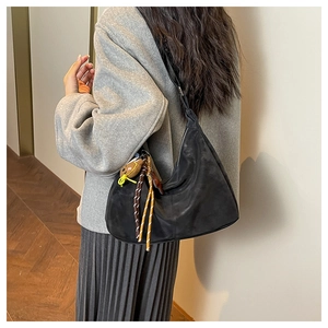 Détail du sac hobo en daim noir avec pendentif personnage et bandoulière tressée
