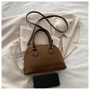 Detail of brown leopard print shell bag with matte texture and golden hardware