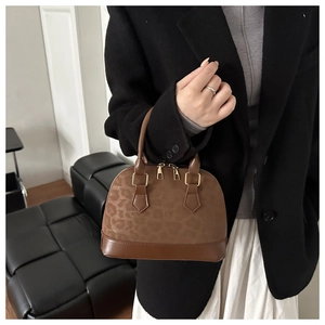 Detailed view of leopard print shell bag with golden hardware and smooth leather handles