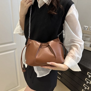 Brown pleated faux leather crossbody bag with silver chain strap worn by a model