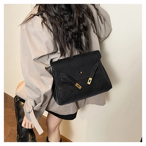 Detail of a vintage black leather briefcase with gold buckle worn as a shoulder bag