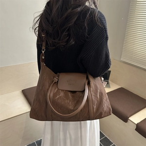 Brown textured large travel tote bag with shoulder strap shown in a cozy indoor setting