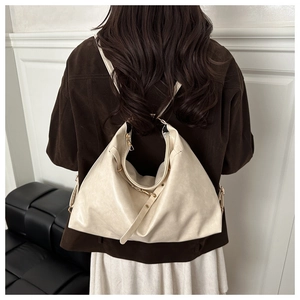 Detail of cream-colored hobo bag showing supple faux leather texture and golden hardware