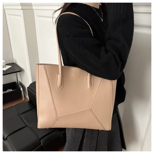 Detail view of beige leather tote bag with geometric stitching and golden logo on front