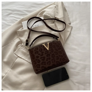 Macro shot of faux calf hair leopard print crossbody bag with gold V-shaped metal hardware