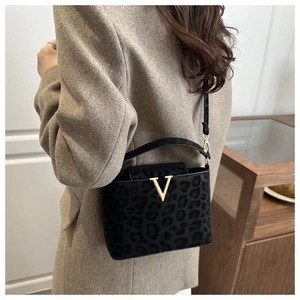 Détail d'un sac à main léopard gris avec logo V doré et texture en cuir suédé mat