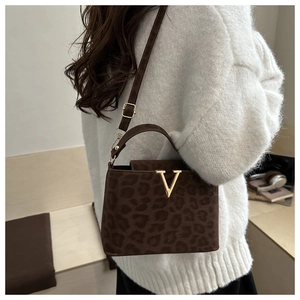 Close-up of leopard print handbag with gold V-shaped metal buckle on white sweater background