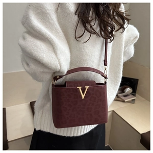 Detail of burgundy leopard print handbag with gold V-shaped logo and top handle